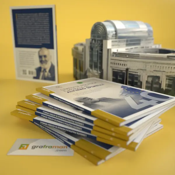 Pila di copie del libro su Altiero Spinelli con il modellino del Parlamento Europeo sullo sfondo - Graframan