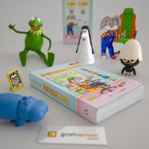 Rendering 3D ravvicinato dall'alto della copertina frontale di "Pupazzi Story" circondata da pupazzi giocattolo di Kermit, Carmencita e Calimero - Graframan